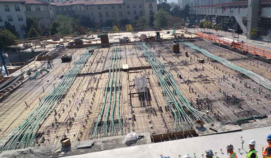 Large construction site with reinforced concrete foundation and green metal rebar grid laid out systematically
