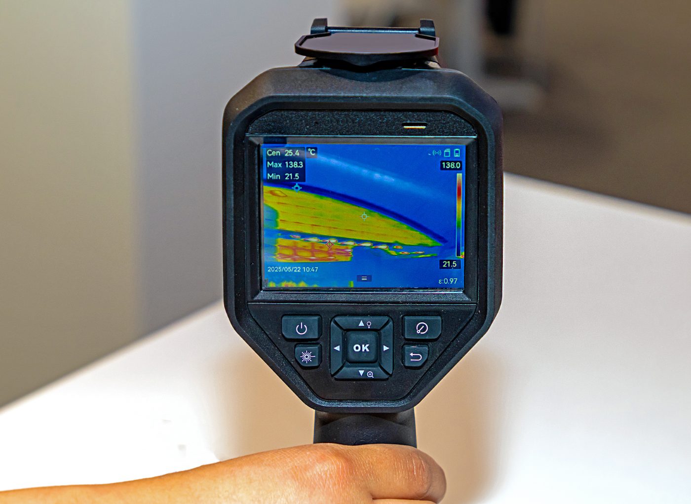 Thermal imaging camera displaying colorful heat map with temperature readings on handheld device